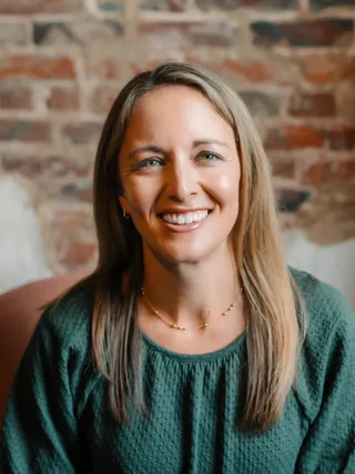 Megan Roberts, smiling, in front of a brick wall.